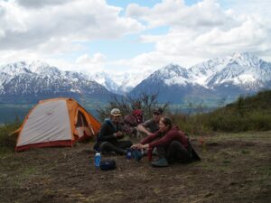 people sitting down snowy mountains tent