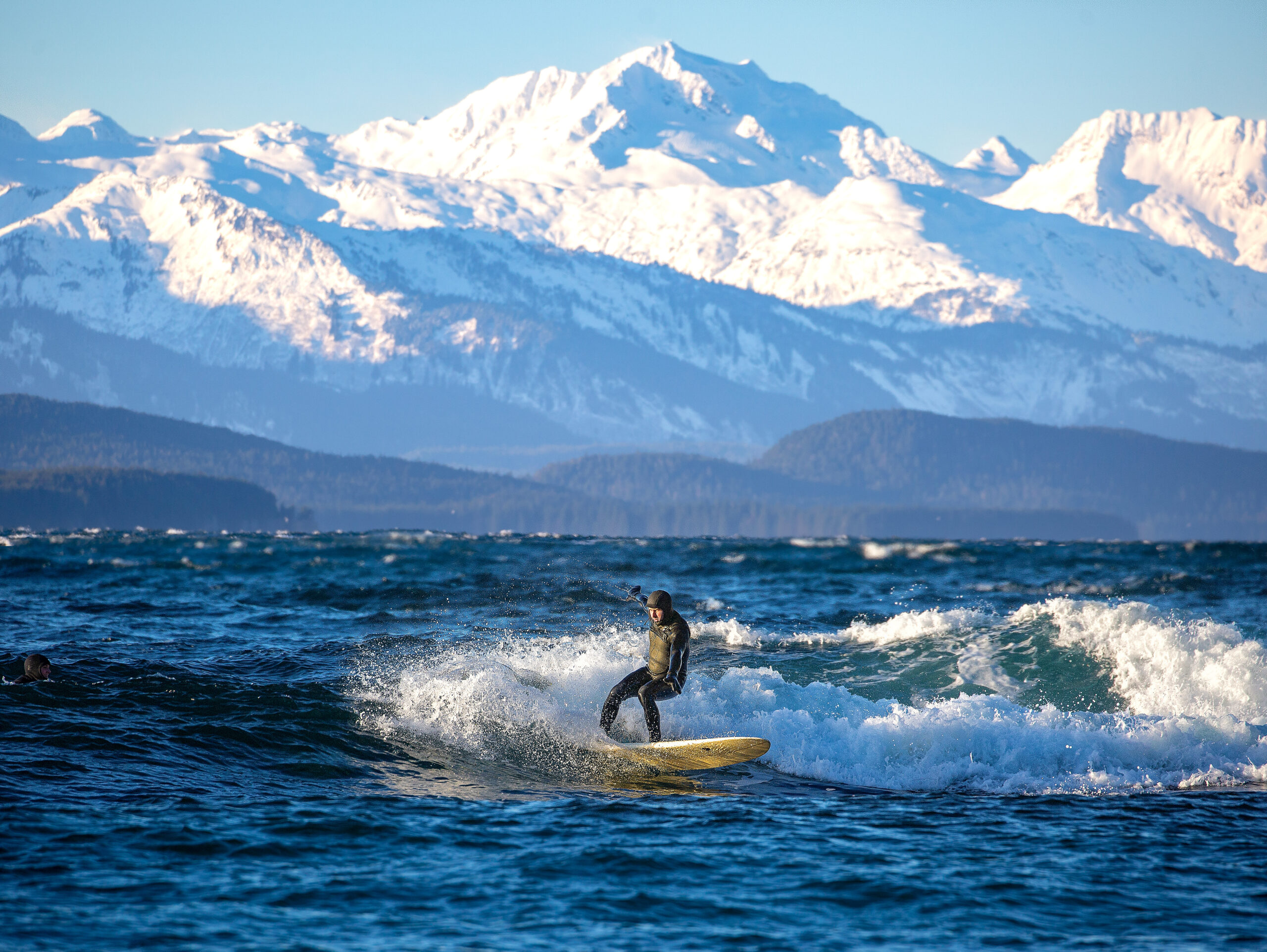 Person surfing near snowy mountains