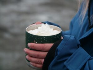 person holding hot cocoa in a parka