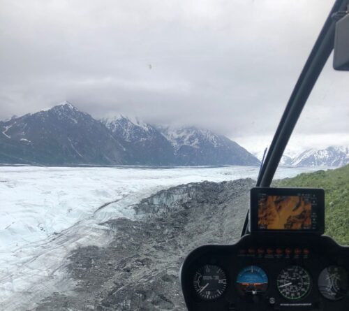 helicopter flying over glacier