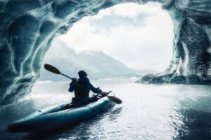 person sea kayaking under glacier