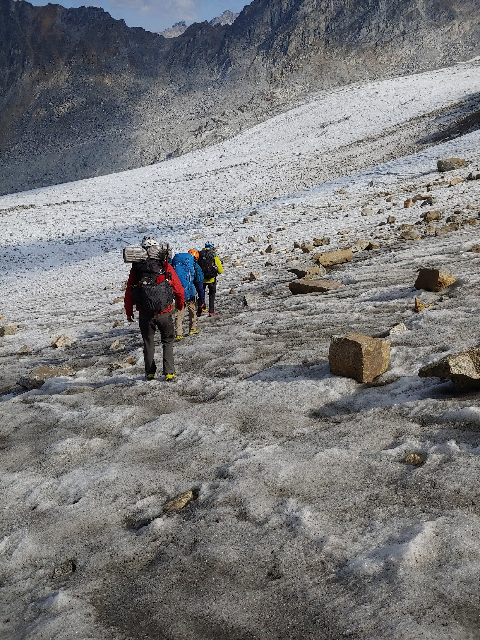 people walking across ice and rocks with backpacks on