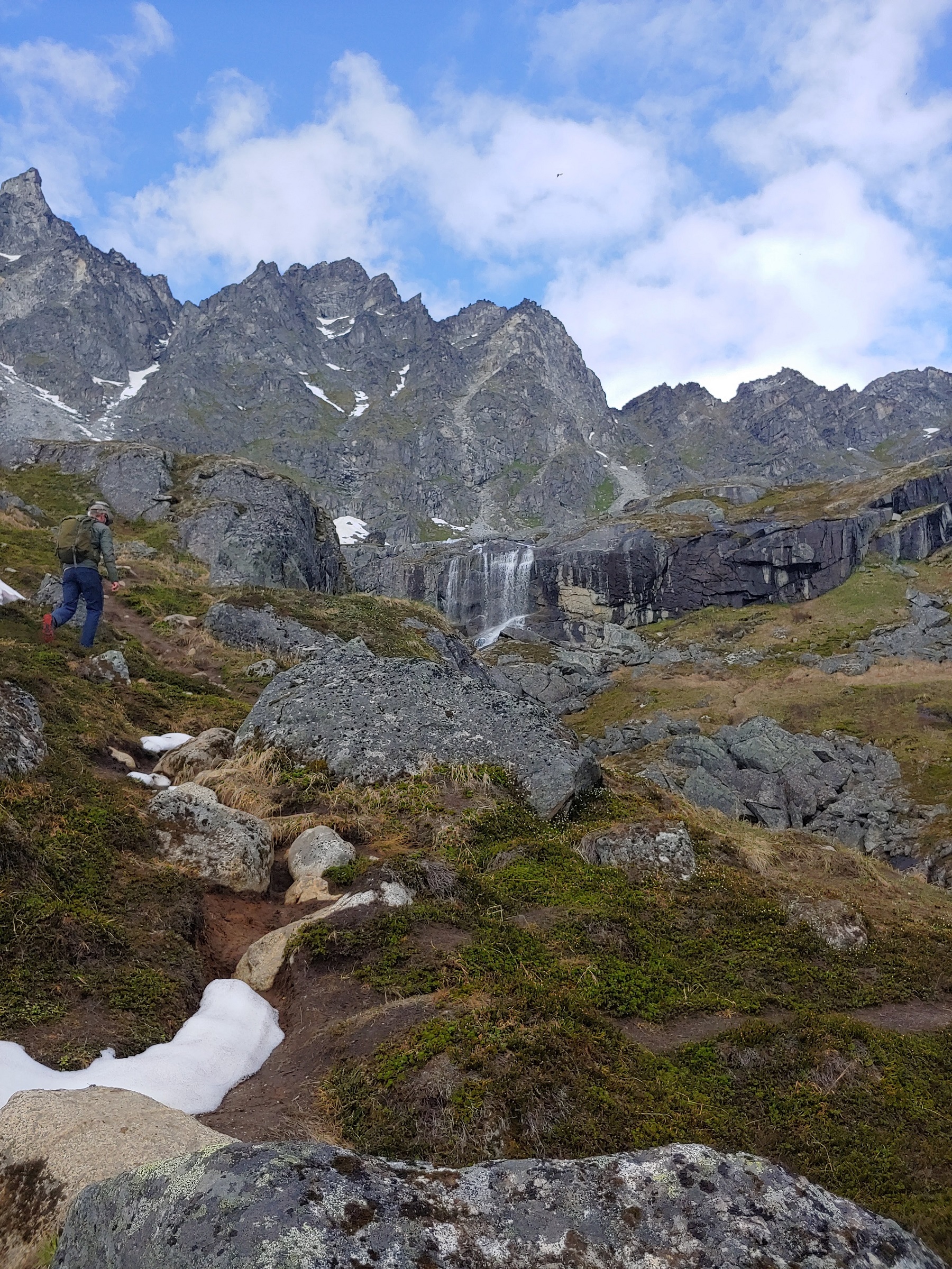 person running up trail near waterfall