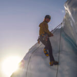 sun setting as ice climber tops out on glacier wall