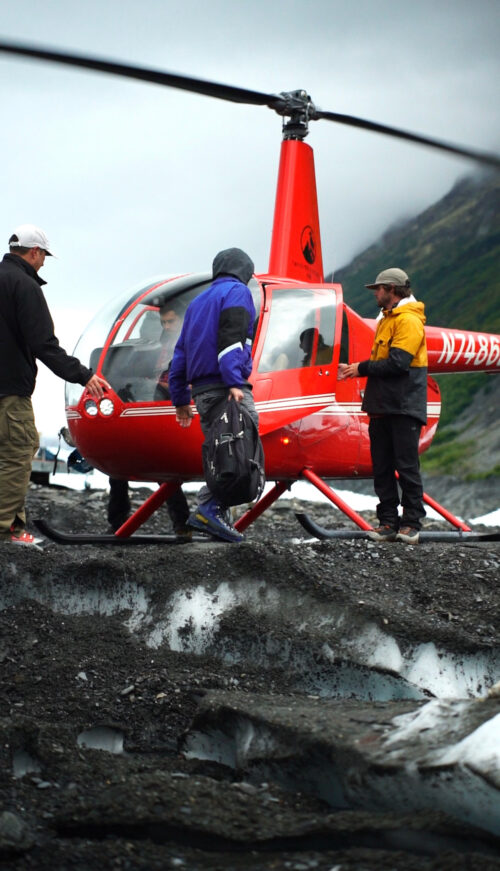 people group around helicopter unloading bags