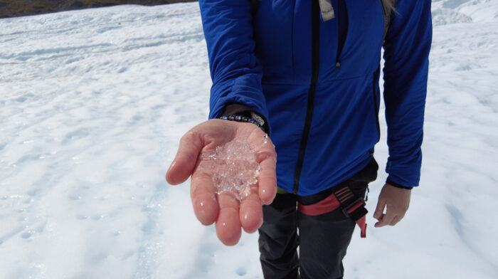 person holding ice shard in hand with blue jacket