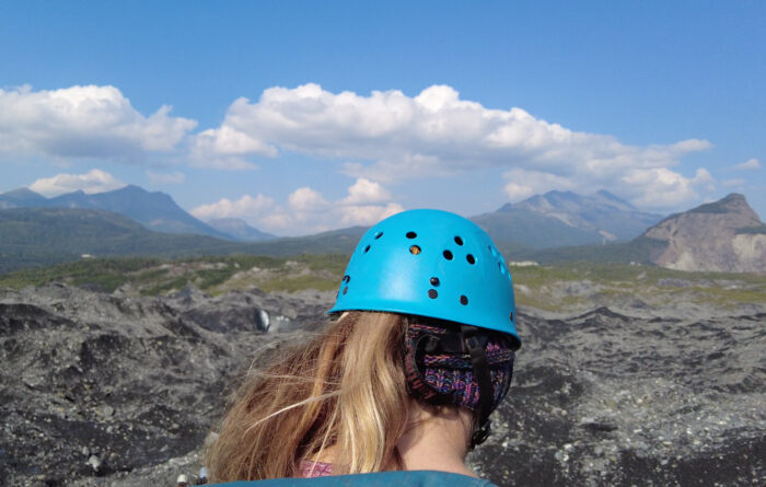 person with blue helmet on looks out towards mountains