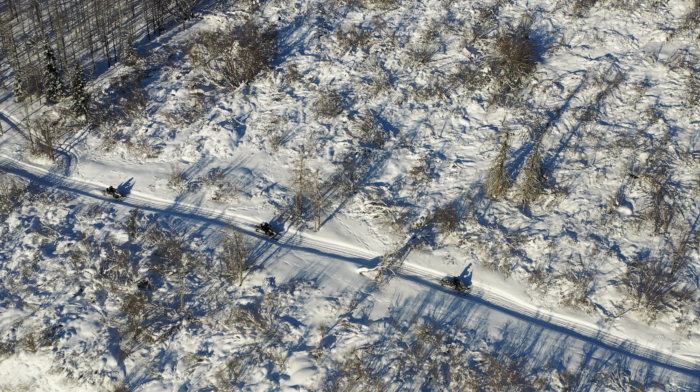 snowmobiles riding across snowy Alaska field