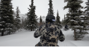 snowmobiler with black helmet and pine trees ahead